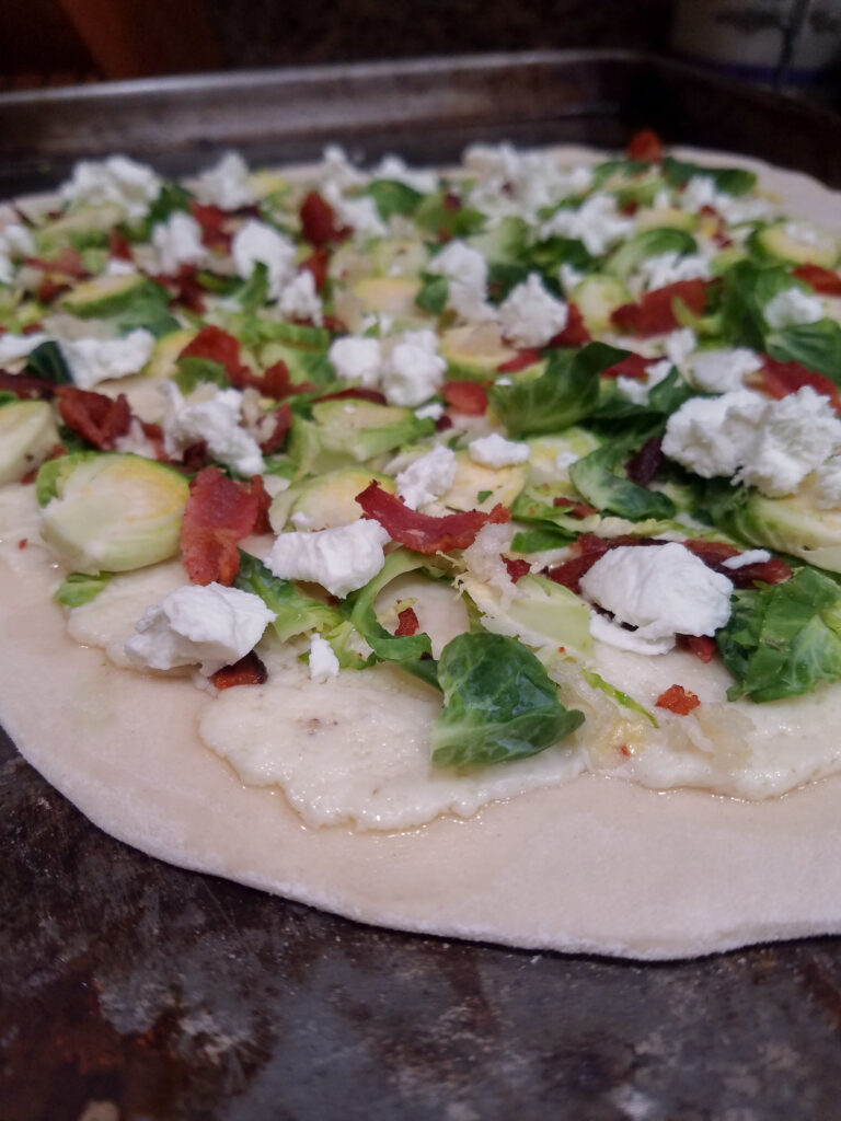 Bacon Brussel Sprout Goat Cheese Pizza made before it goes into the oven.
