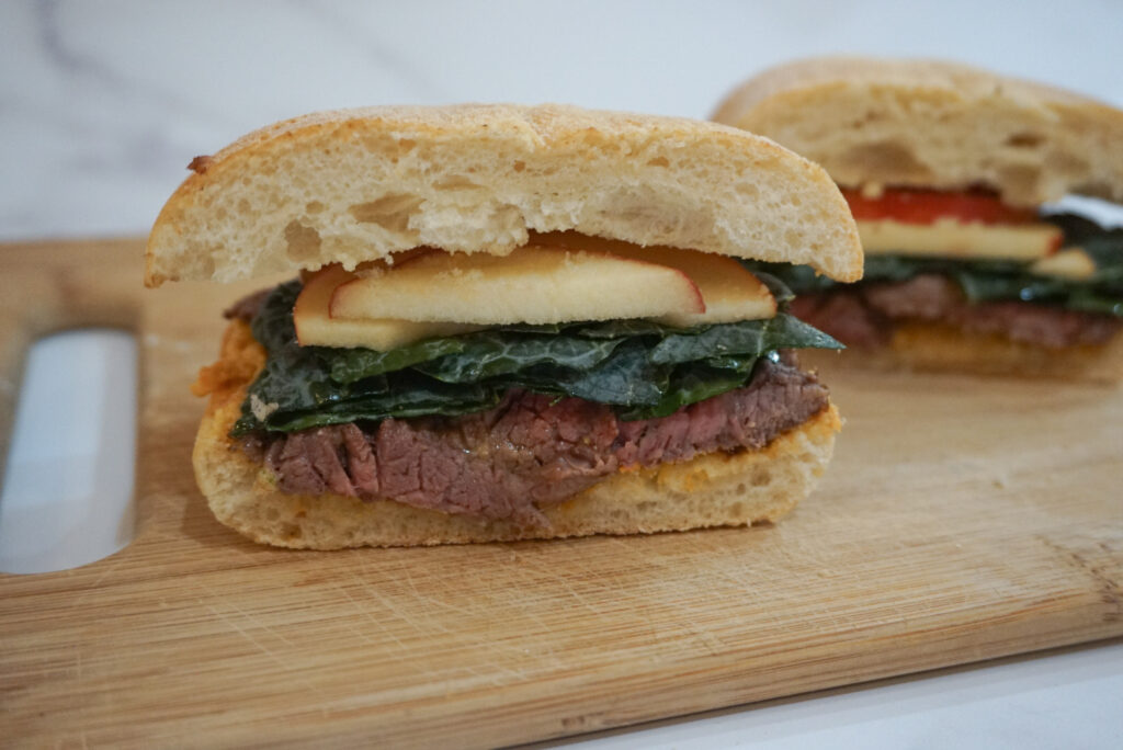 An assembled and cut shot of the Fall Steak Sandwich with a Goat Cheese Butternut Squash Spread