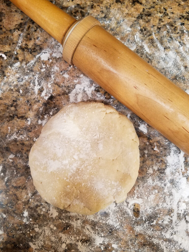 Cream cheese pie crust on a floured counter with a rolling pin.