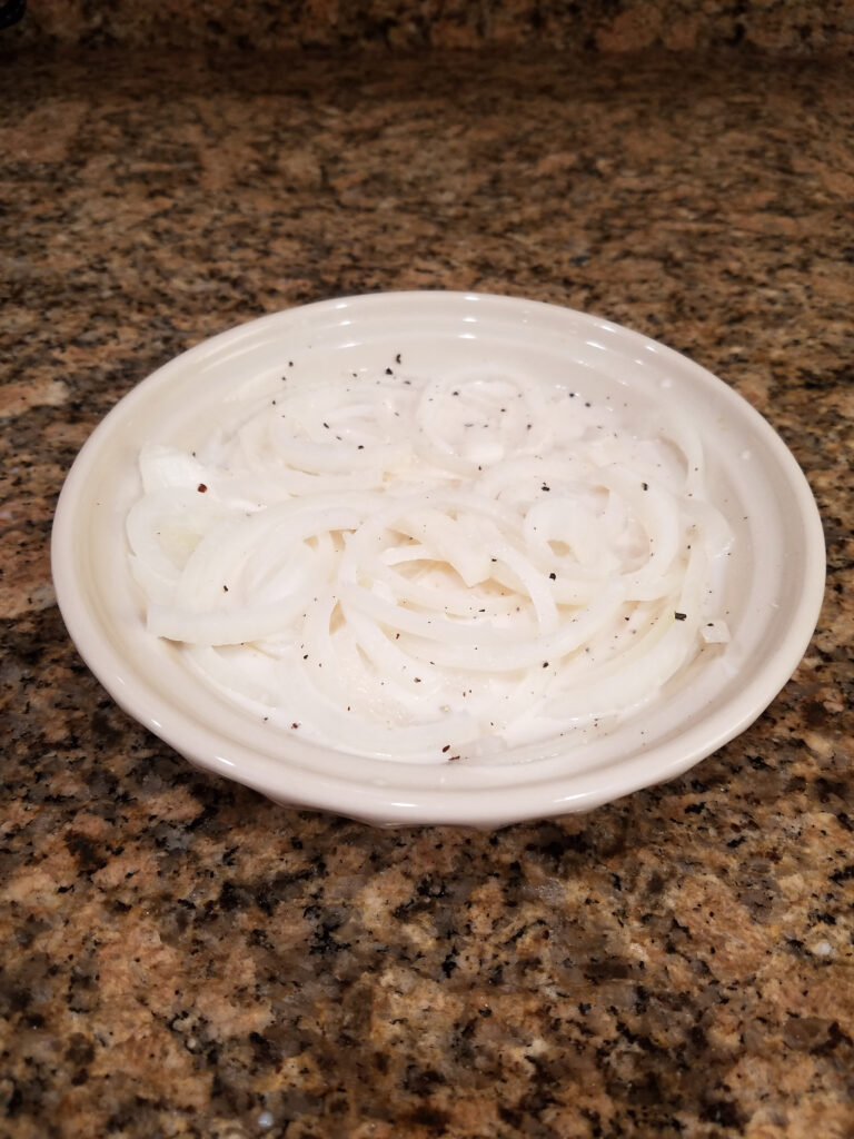 Sliced onions soaking in milk mixture.