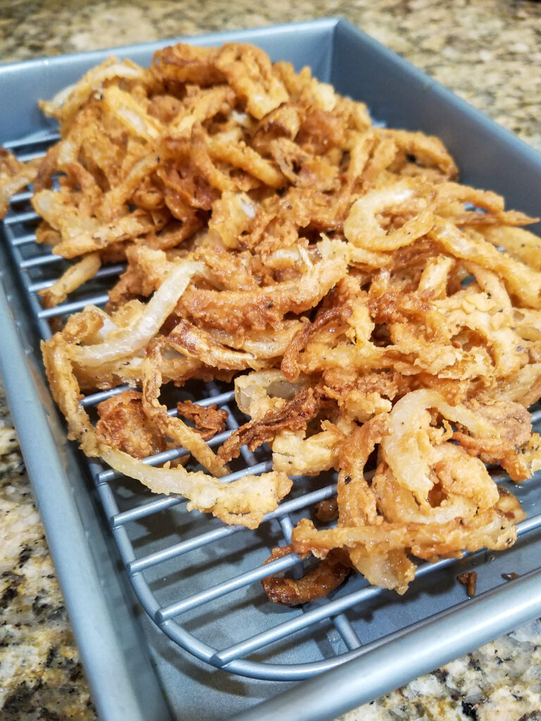 Fried onion strings draining on a rack.