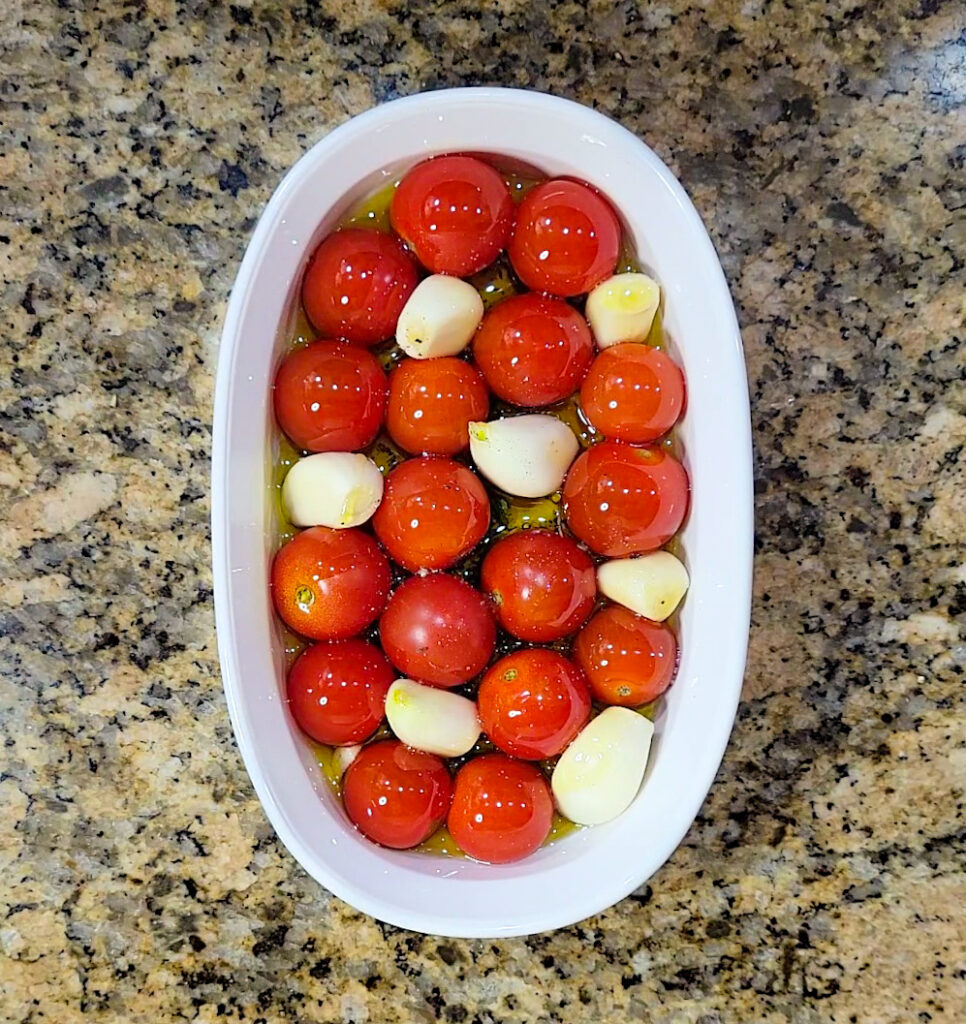 A dish packed full with cherry tomatoes and garlic to bake. 