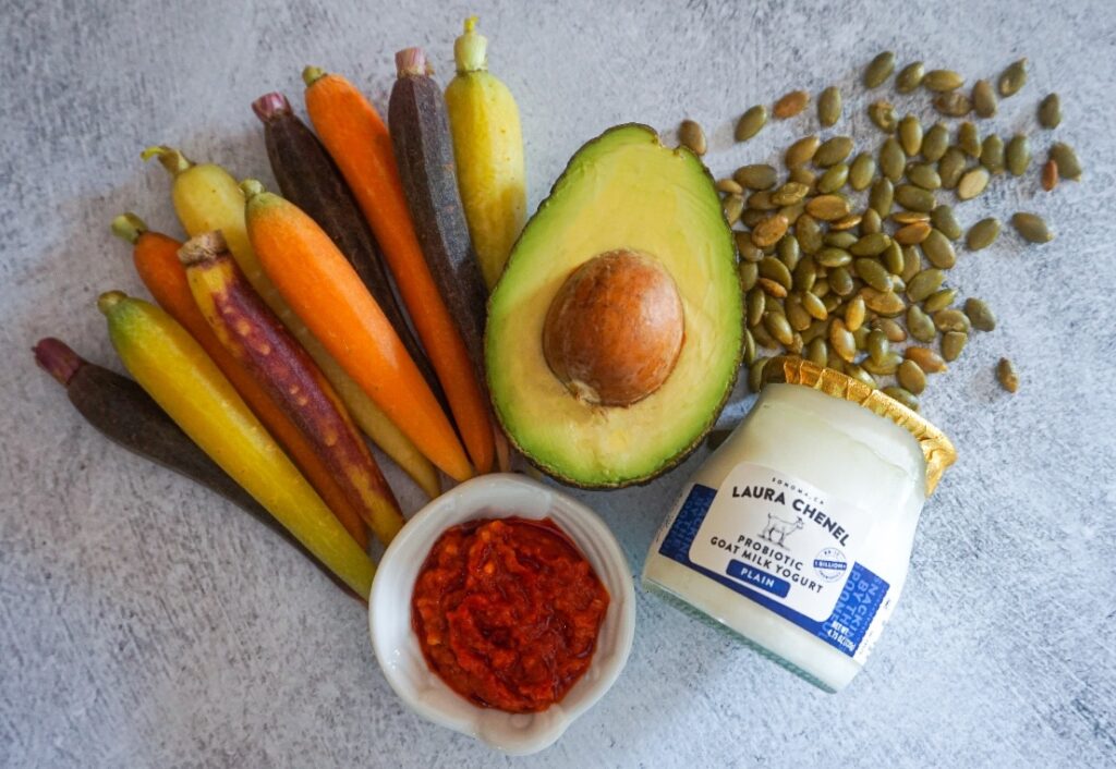 All of the ingredients needed to make harissa roasted carrots and an avocado yogurt sauce. 