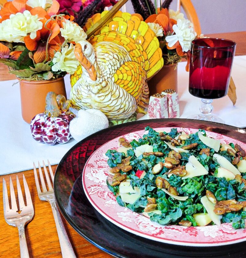 A table setting with a plate full of candied pumpkin seed kale salad.
