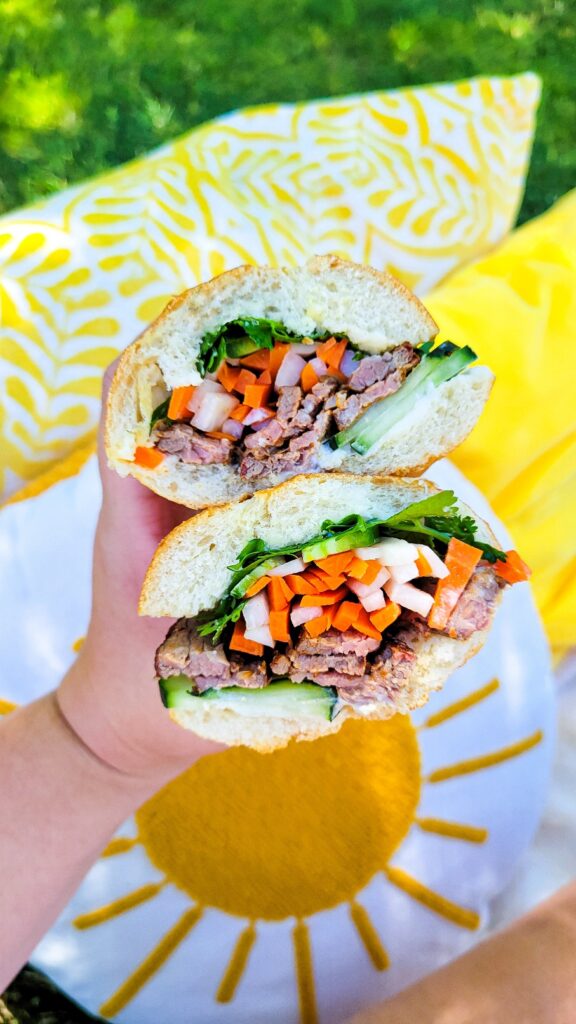 Holding the grilled banh mi sandwich cut in half.
