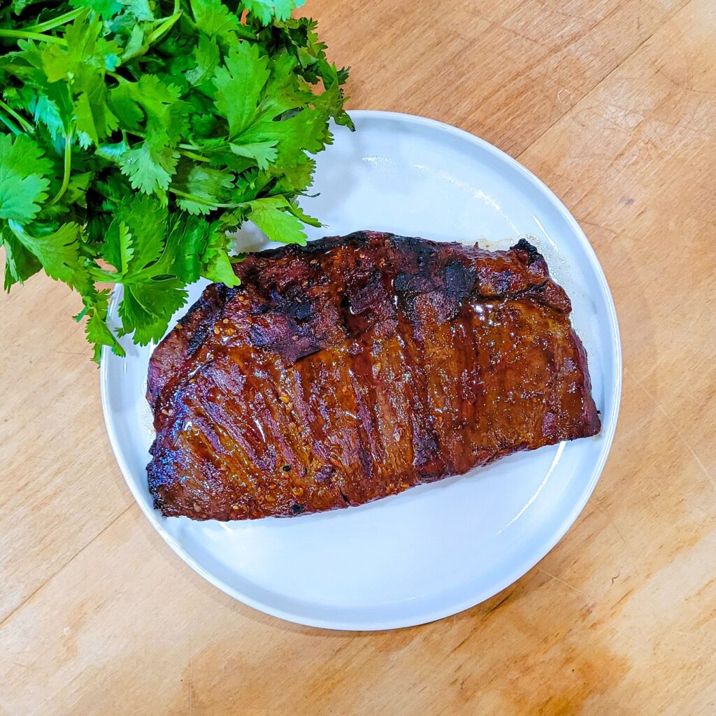 The cooked flank steak resting on a plate.